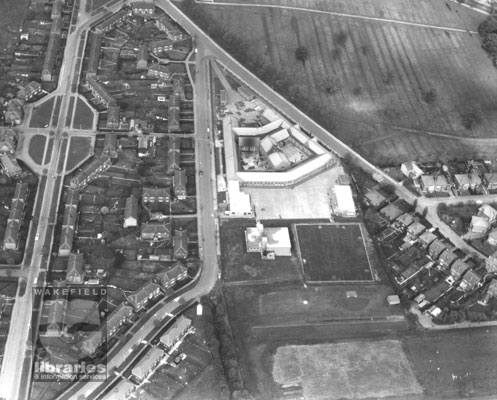 A black and white aerial photograph (Aerofilms reference number A182999) showing Sandal Magna.  Manygates Middle School is in the centre, with Milnthorpe Lane on the left and Manygates Lane on the right.  Duke of York Avenue runs down the left side of the photograph.  Miller Avenue is on the right.  Internal Reference: WR (LS) Aerial photos 182999