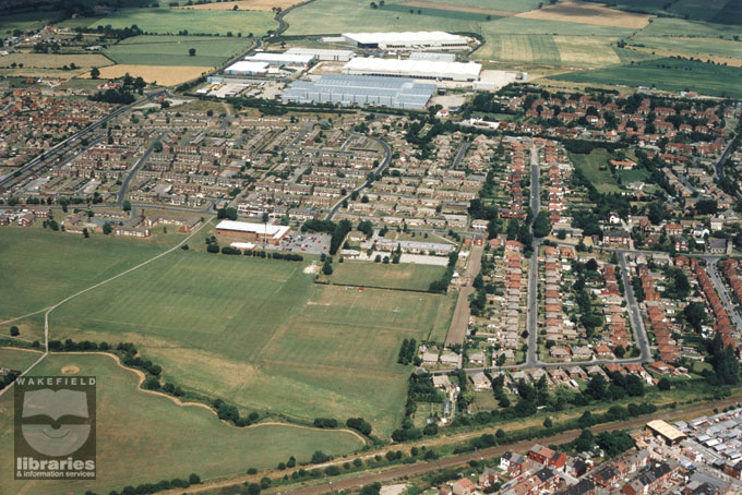 A colour aerial photograph of Ash Grove First School, South Elmsall.  The school is in the centre of the photograph and has a playground and playing fields at the back, beyond which are open playing fields.  At the side of the school is Minsthorpe Swimming Baths, and nest to them old people's flats, and then an old people's residential home.  At the top of the picture is Dale Lane Industrial Estate.  There are houses all around this area.  Internal Reference: WR (LS)