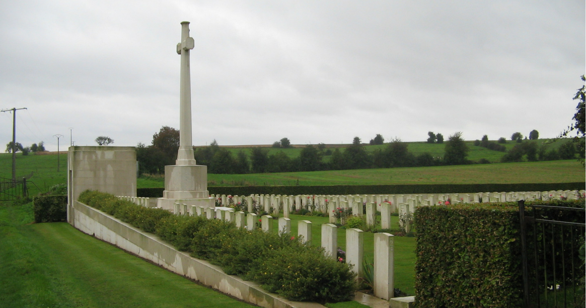 Photo of Forceville Communal Cemetery. A white cross memorial and rows of headstones.