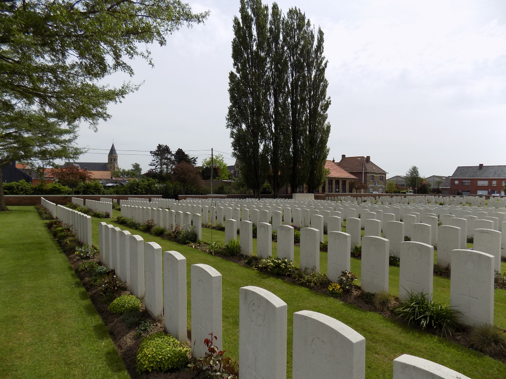 Photo of Voormezeele Enclosure N°3. Rows of white headstone in a lawned area with rows of plant in front of each line of headstones.