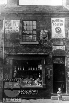 A black and white photograph showing the premises of J.C.Lambert, confectioner and tobacconist, in Eastmoor.  On the wall are old advertising posters.  In the window, jars of sweets can be seen.  The building later became part of the Fox and Grapes public house.  Internal Reference: WR (LS) Frith Collection