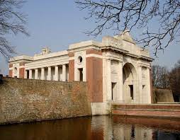 Photo of Menin Gate Ypres memorial. White stone and red brick with columns  building with water in front.