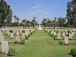 Fayid War Cemetery with rows of gravestones. The Cross of Sacrifice is in the background