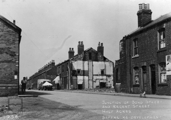 A black and white photograph of terrace houses on the junction of Bond Street and Regent Street, Castleford, during demolition.  A lorry and a large van are parked I the street and it looks as though some houses are still lived in.  Internal Reference: CA YILLUS 1666