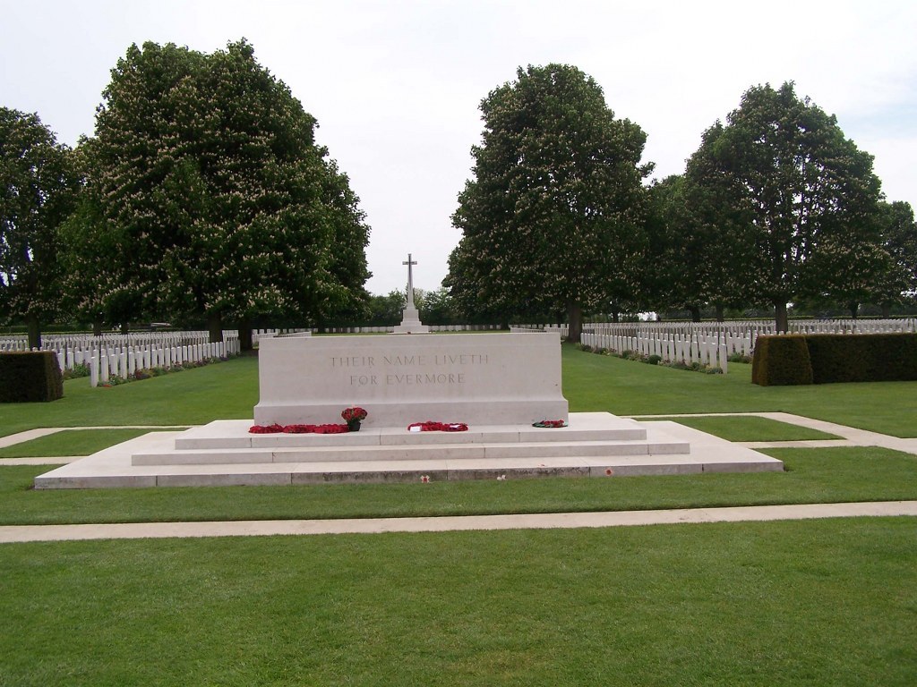 Bayeux War Cemetery. A large stone with the engraving "Their name liveth forevermore" can be seen with a large cross and gravestones in the background    g "their name