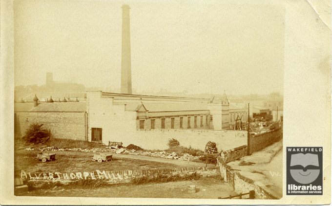 A black and white postcard showing the Alverthorpe Mills, taken around 1900, with Alverthorpe Church in the background.  The mills were owned by the Colbeck Brothers, local woollen manufacturers.  The mill's single brick chimney can be seen left centre.  Internal Reference: Private Collection