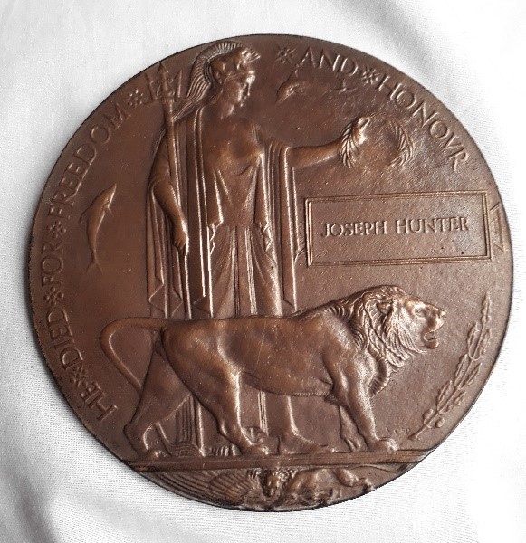 Joseph's bronze memorial plaque showing britannia standing behind a lion with a laurel wreath in her left hand and words inscribed round the edge read he died for freedom and honour. His name is inscribed