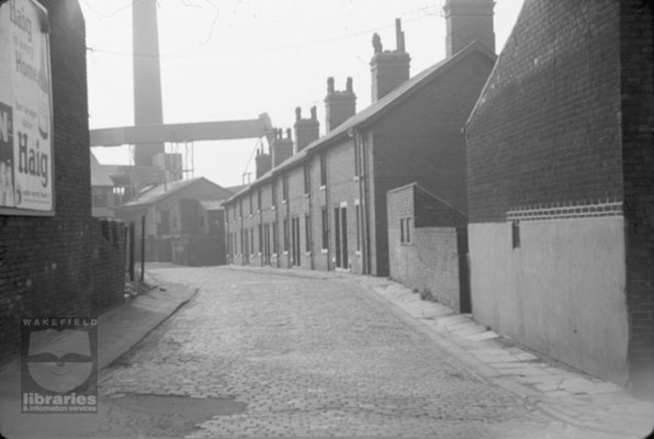 A black and white slide showing Pauline Terrace, Hightown, Castleford, leading to John Lumb's glassworks.  John Lumb's were later taken over by United Glass.  Internal Reference: Castleford and District Historical Society Slide Collection