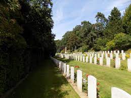 Photo of St Valery-en-Caux Franco British Cemetery. Rows of headstones with a line of trees to either side.
