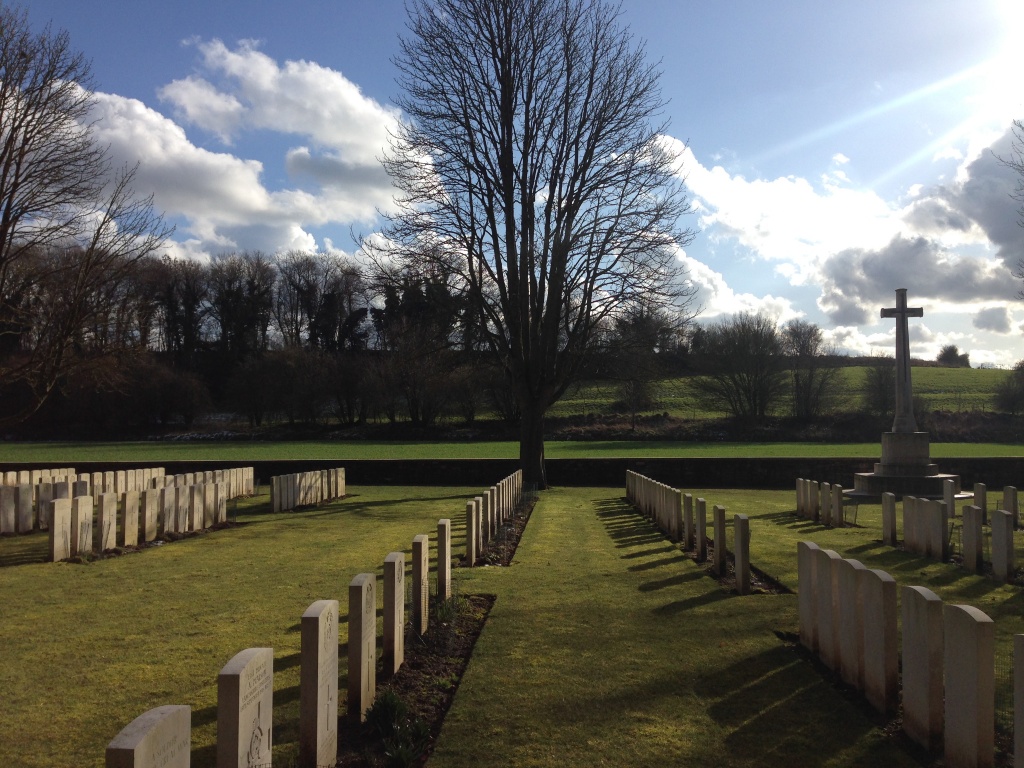 Photo of Blighty Valley Cemetery. Rows of headstones with a cross memorial to the right.