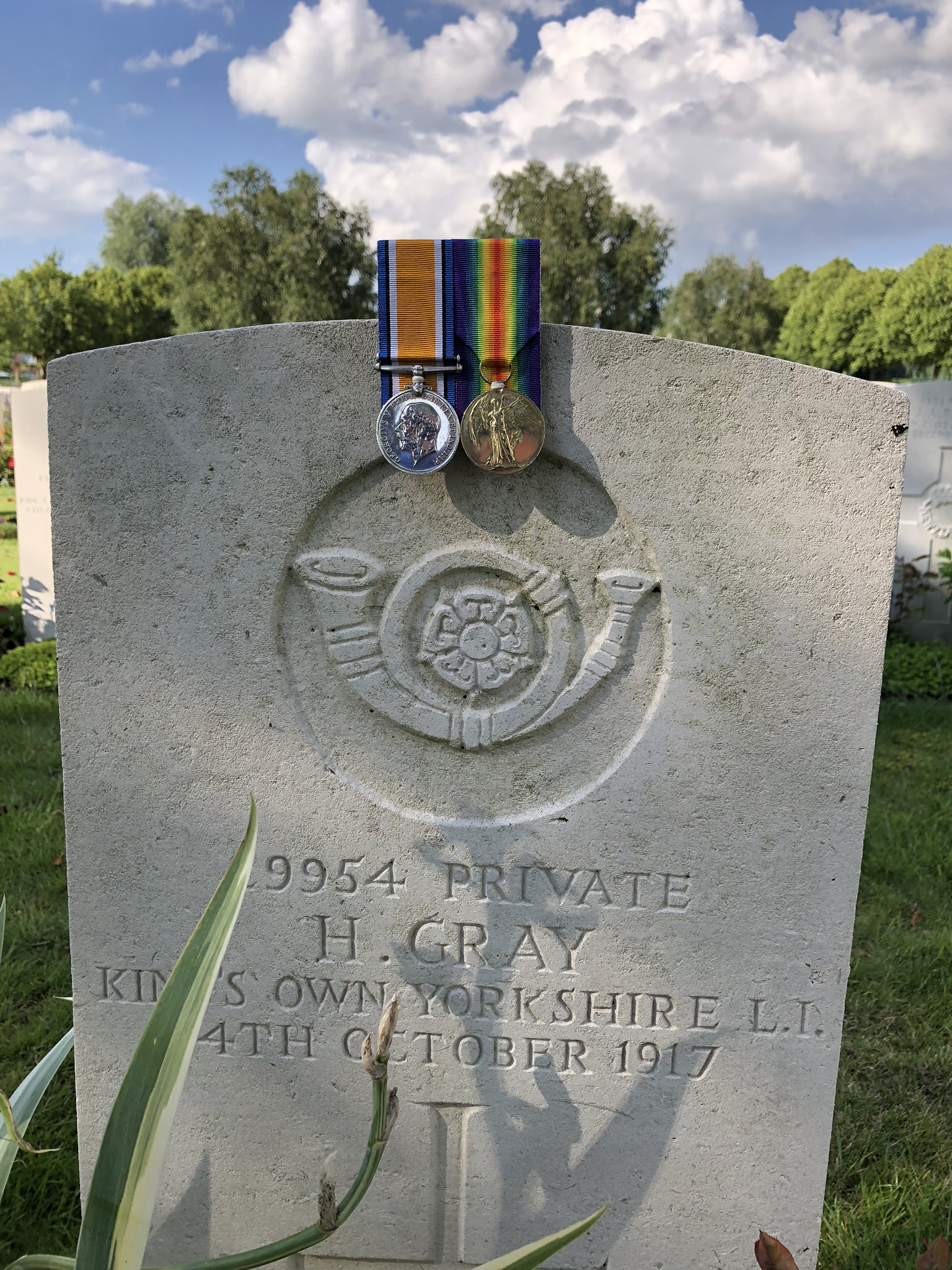 Gravestone of Harry Gray. His medals are draped over the top of the gravestone.