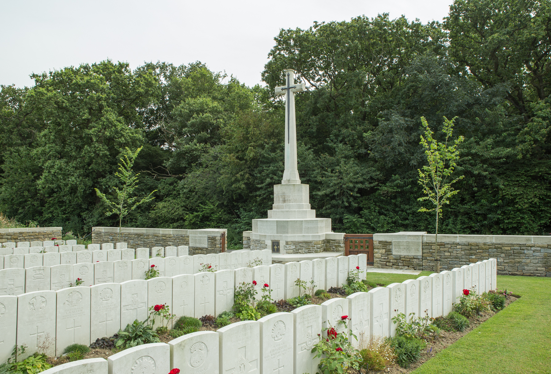 Ebblinghem Military Cemetery with rows of gravestones and the Cross of Sacrifice in the background