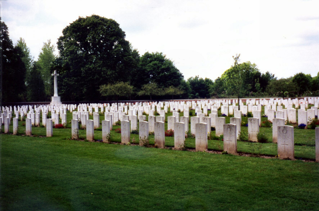 Hebuterne Military Cemetery with rows of gravestones and trees in the background