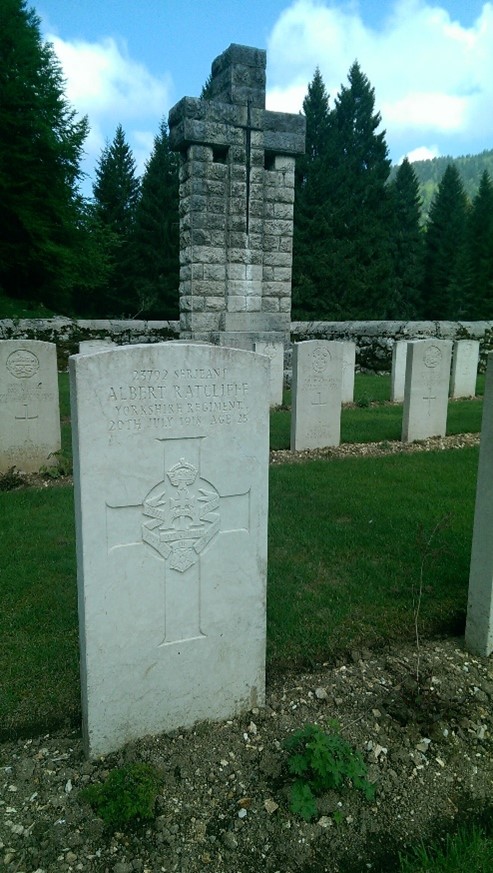 colour photograph of Albert's grave giving his name and army details, date of his death and a large cross is inscribed underneath with his regimental badge in the middle of it. Other gravestones can be seen in the background as can some trees