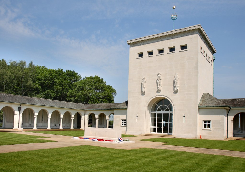 a tall white building with a white colonnade to the side and mown grass in the front
