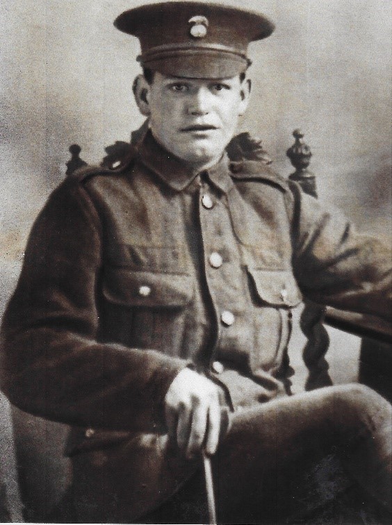 John savage sitting in a chair wearing his army uniform and cap
