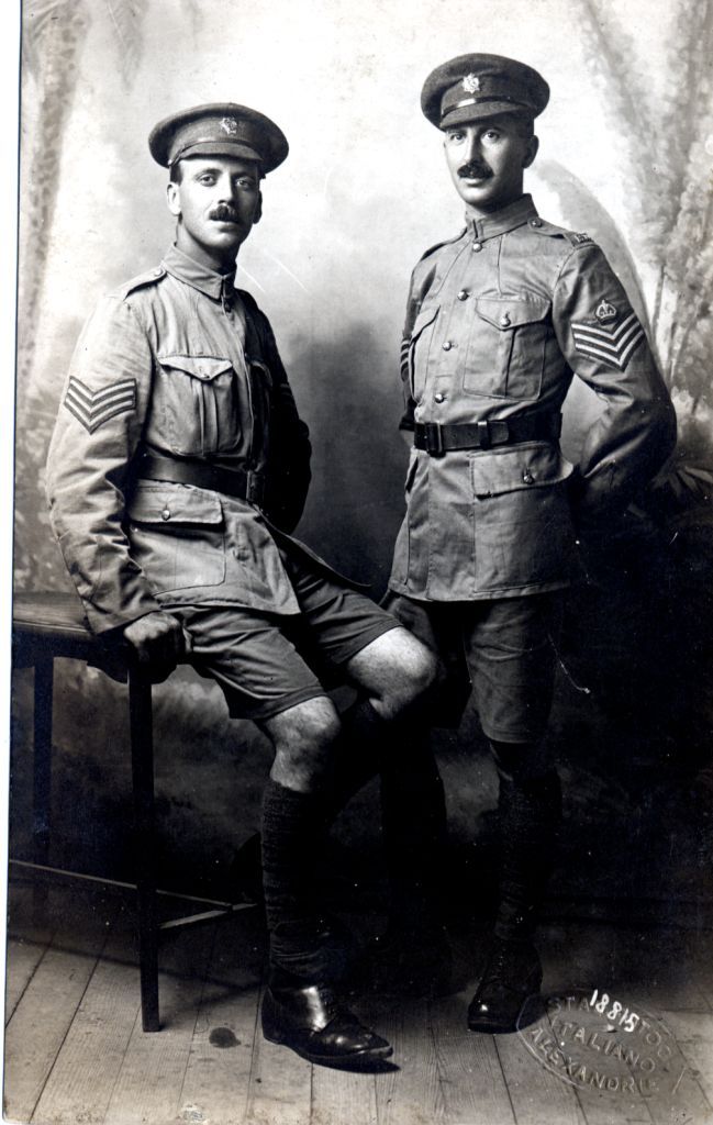 alfred sitting down in his army uniform with another soldier standing beside him