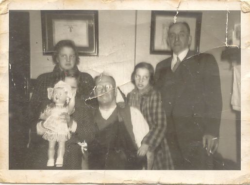 Family photograph of Alfred sitting down, his son Alfred and his two granddaughters