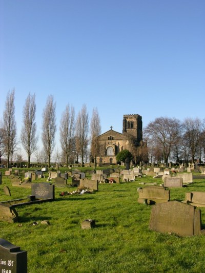 a cemetery with gravestones. at the top of the hill is a church and some trees
