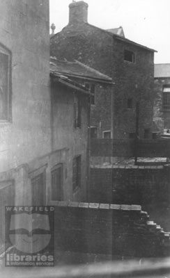 A black and white photograph showing numbers 9 and 11, Camplin Yard, off Stanley Road and the back of  numbers 17 and 21 Greenhill Road, Eastmoor.  The houses were built in close proximity, and were derelict when the photograph was taken between 1930 and 1935.  Saint Andrew's Elementary School, Greenhill Road, can be seen on the far right.  The houses were demolished on the 14th August 1935.  Internal Reference: WR 103, 363.5 WAKW, Photographs of Slum Clearance Properties Book 2