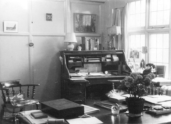 A black and white photograph of the librarian's office at Castleford Library in 1956. Lots of small items personalise the office.  A roll top desk and a table provide work areas.  Notes the bakelite telephone on the window sill.  Internal Reference: CA YILLUS 161