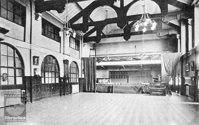 A black and white photograph showing the interior of the Great Hall at Castleford Secondary School, Healdfield Road, Castleford, possibly taken in the post-First World War period. This view looks towards the stage and piano, and the hall features panelling and open beams. The School was built in 1908 and became Castleford Grammar School and then Castleford High School. Internal Reference: CA YILLUS 22