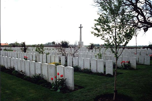 Photo of Mendinghem Cemetery. Rows of white headstones with a white stone cross in the background.