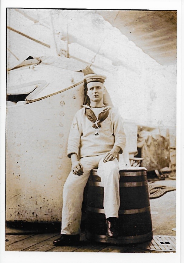 george trueman sitting on a barrel on the desk of a ship wearing his naval uniform