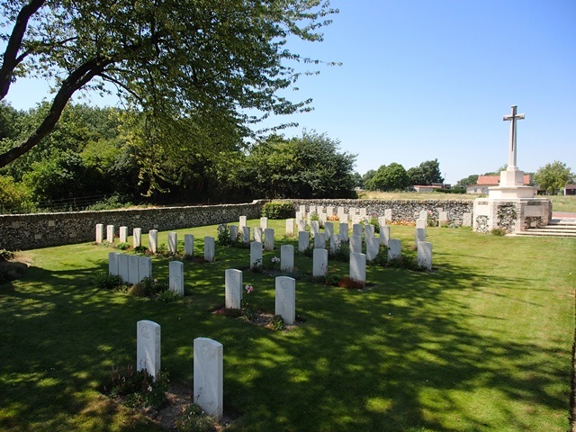 Ervillers Military Cemetery with a small number of gravestones and the Cross of Sacrifice